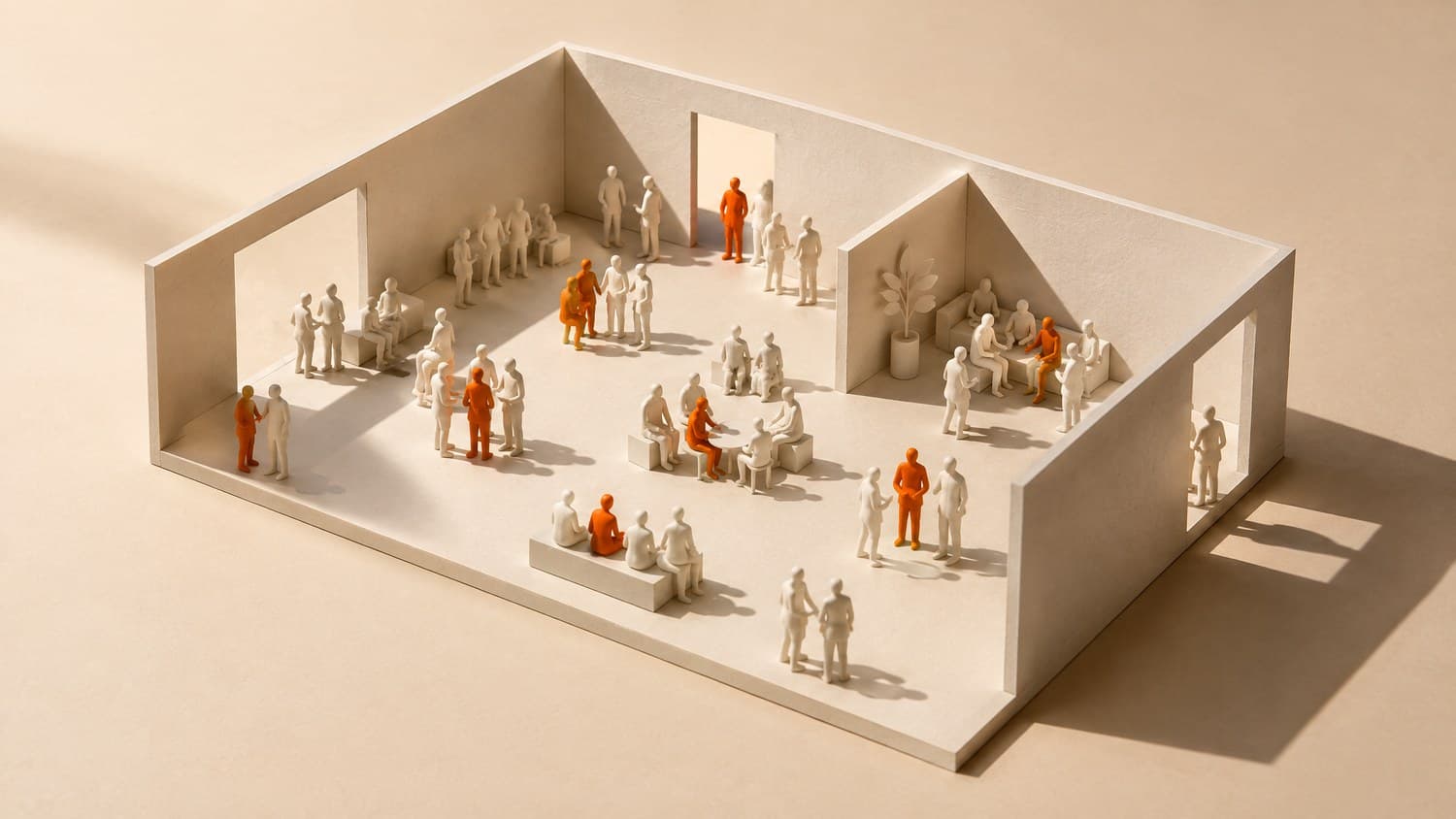 An architect's white card model of an open room, filled with small groups of faceless bone-white figures, a handful of them bright orange